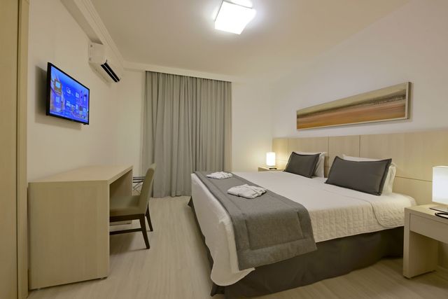 Um quarto de hotel com uma cama king size e uma TV de tela plana.