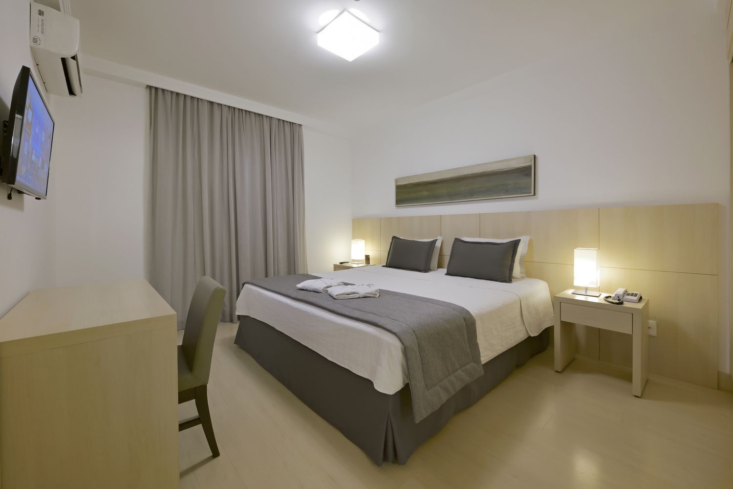 Um quarto de hotel com uma cama king size, um sofá e uma pia.