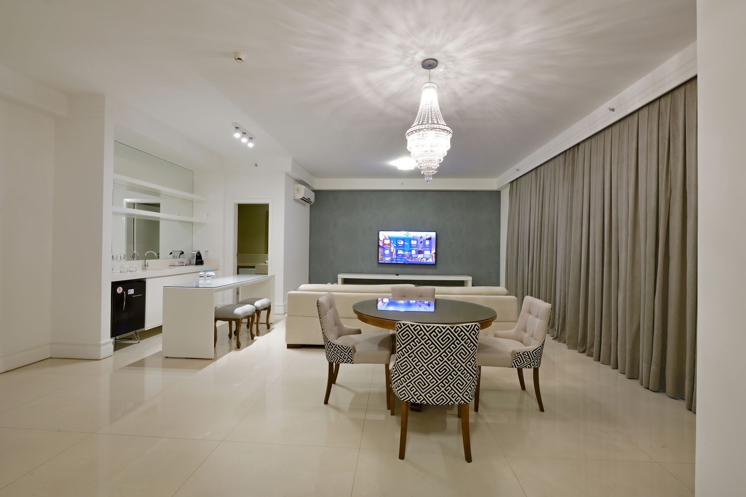 Um quarto de hotel com duas camas, um sofá, uma escrivaninha e uma televisão.