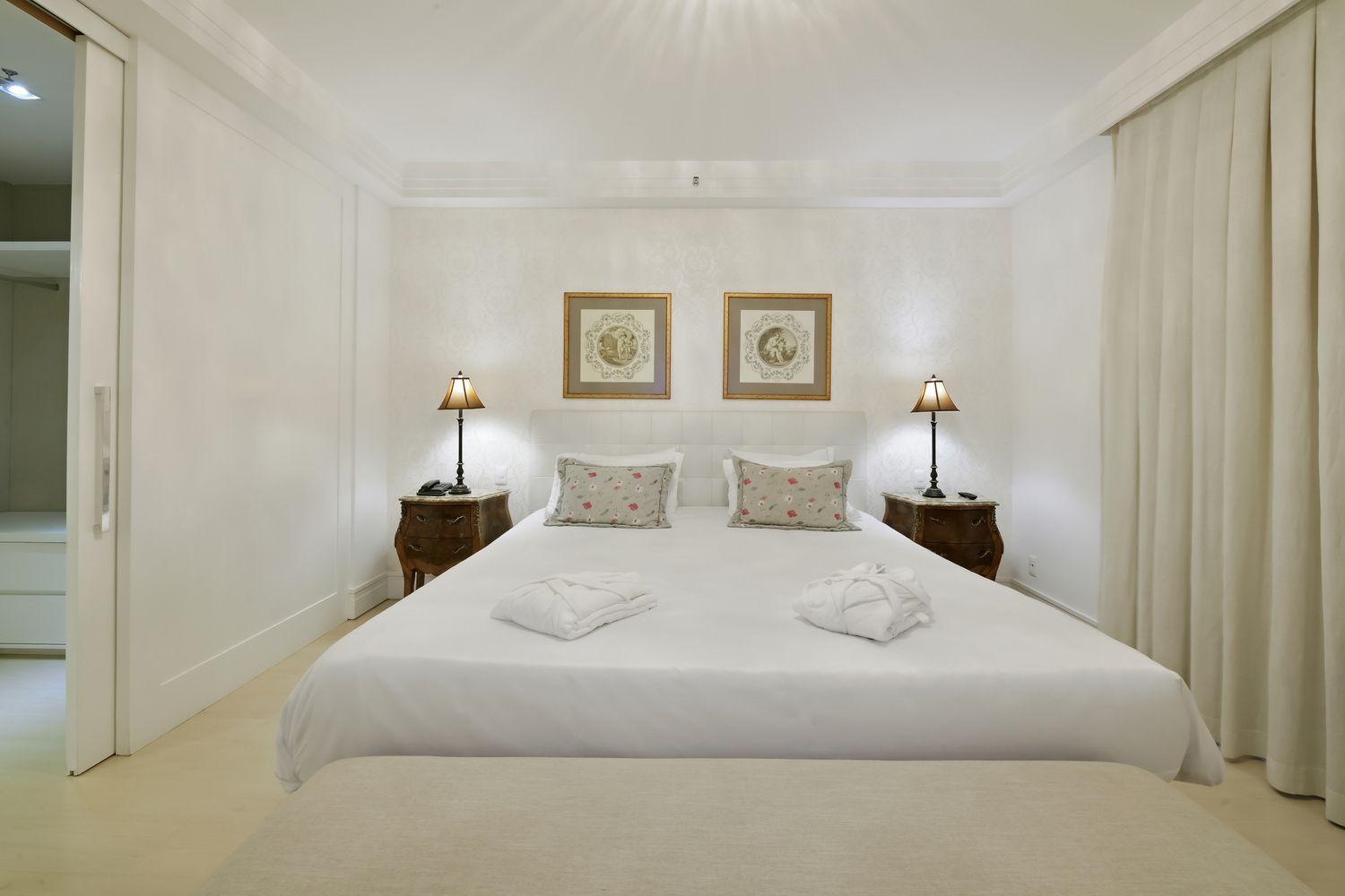 Um quarto de hotel com uma cama, mesa de cabeceira e abajur.