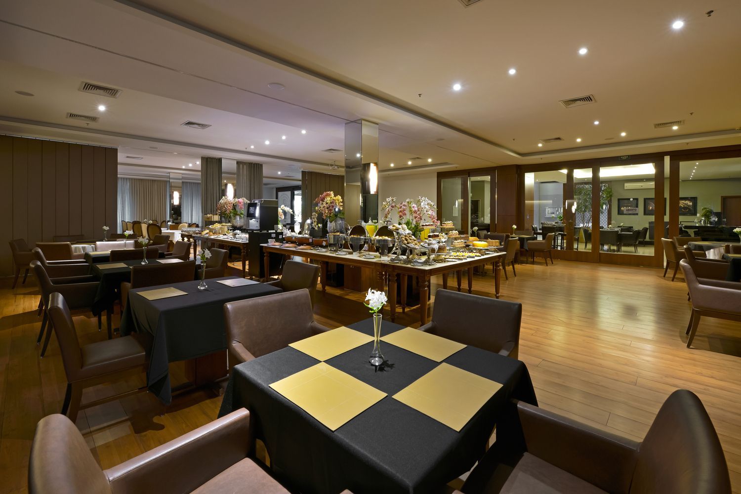 Uma grande sala de jantar com mesas e cadeiras e um bufê.