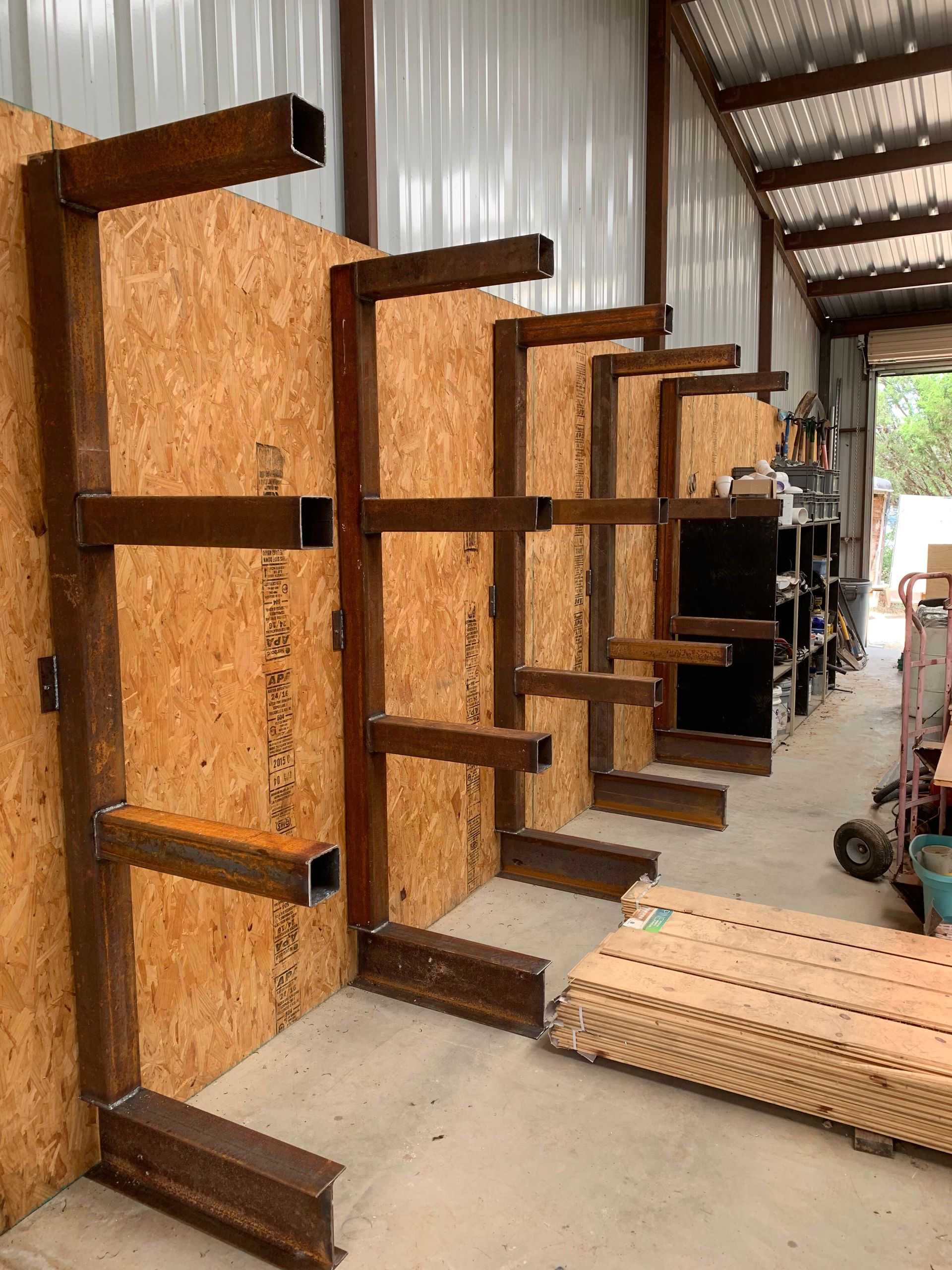 Rows of unfinished wooden cabinets or shelves lined up in a workshop corridor