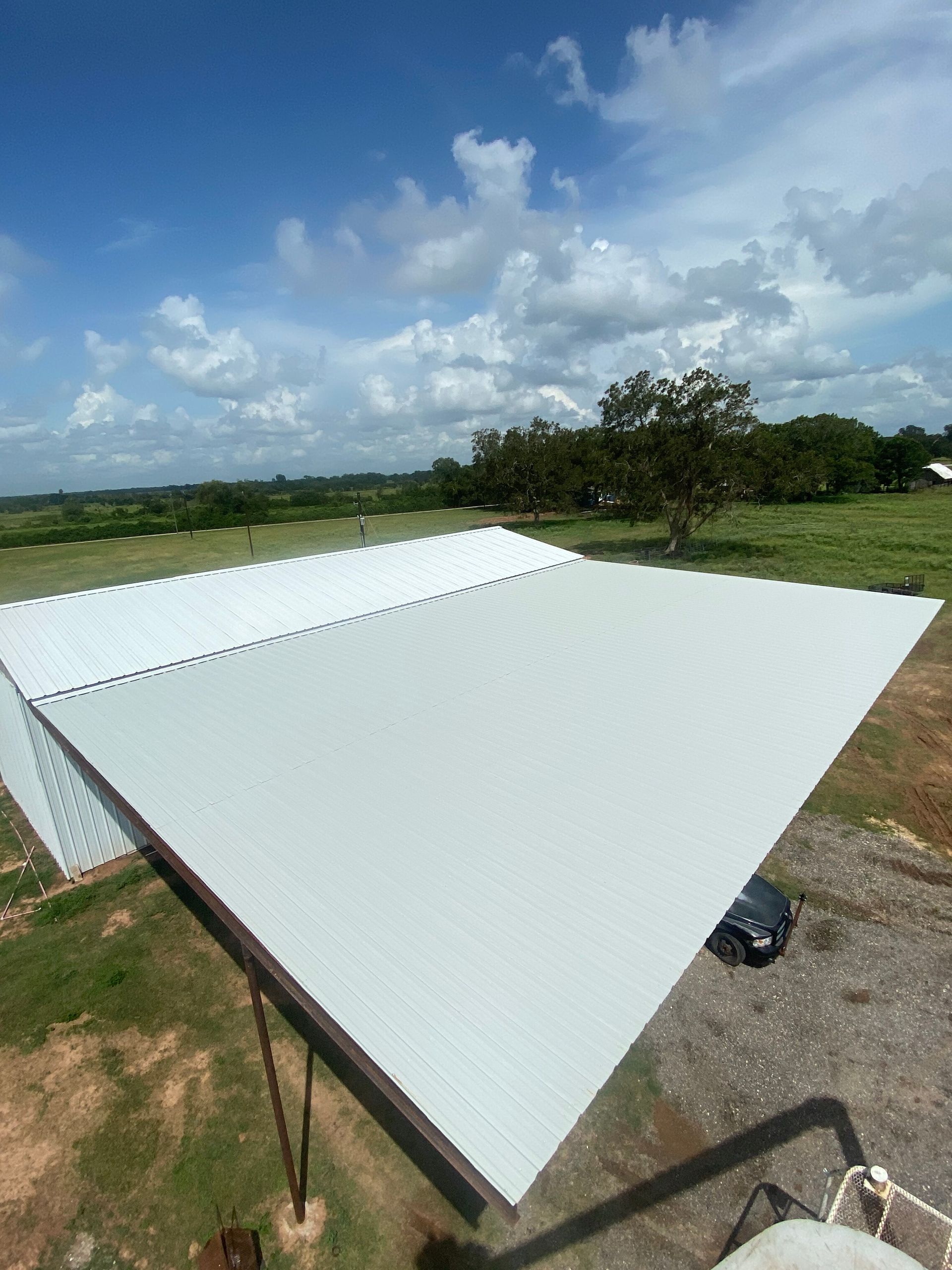 White corrugated metal roof panels under a blue sky in a rural field