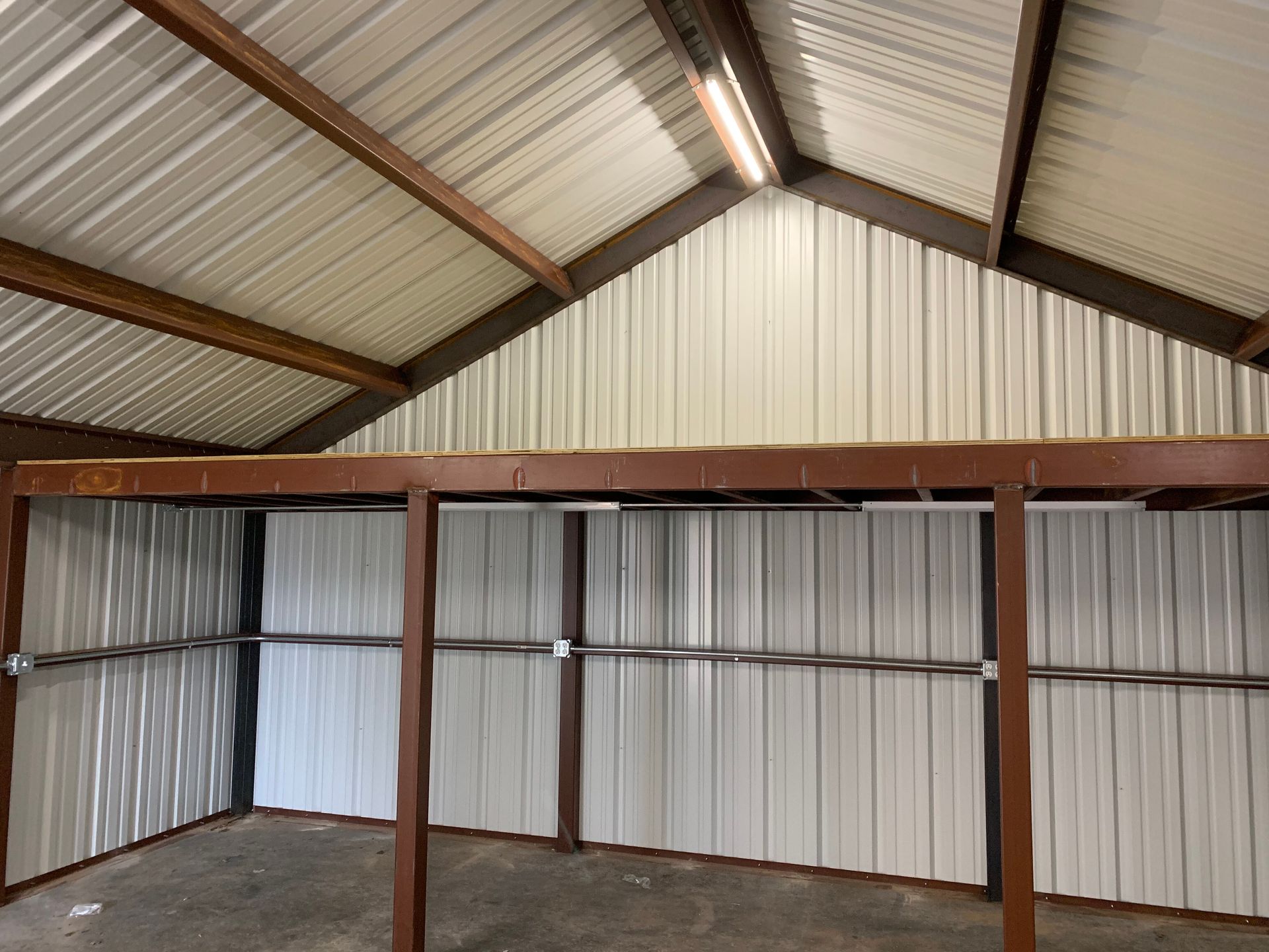Empty metal shed interior with corrugated walls, exposed beams, and a sloped roof