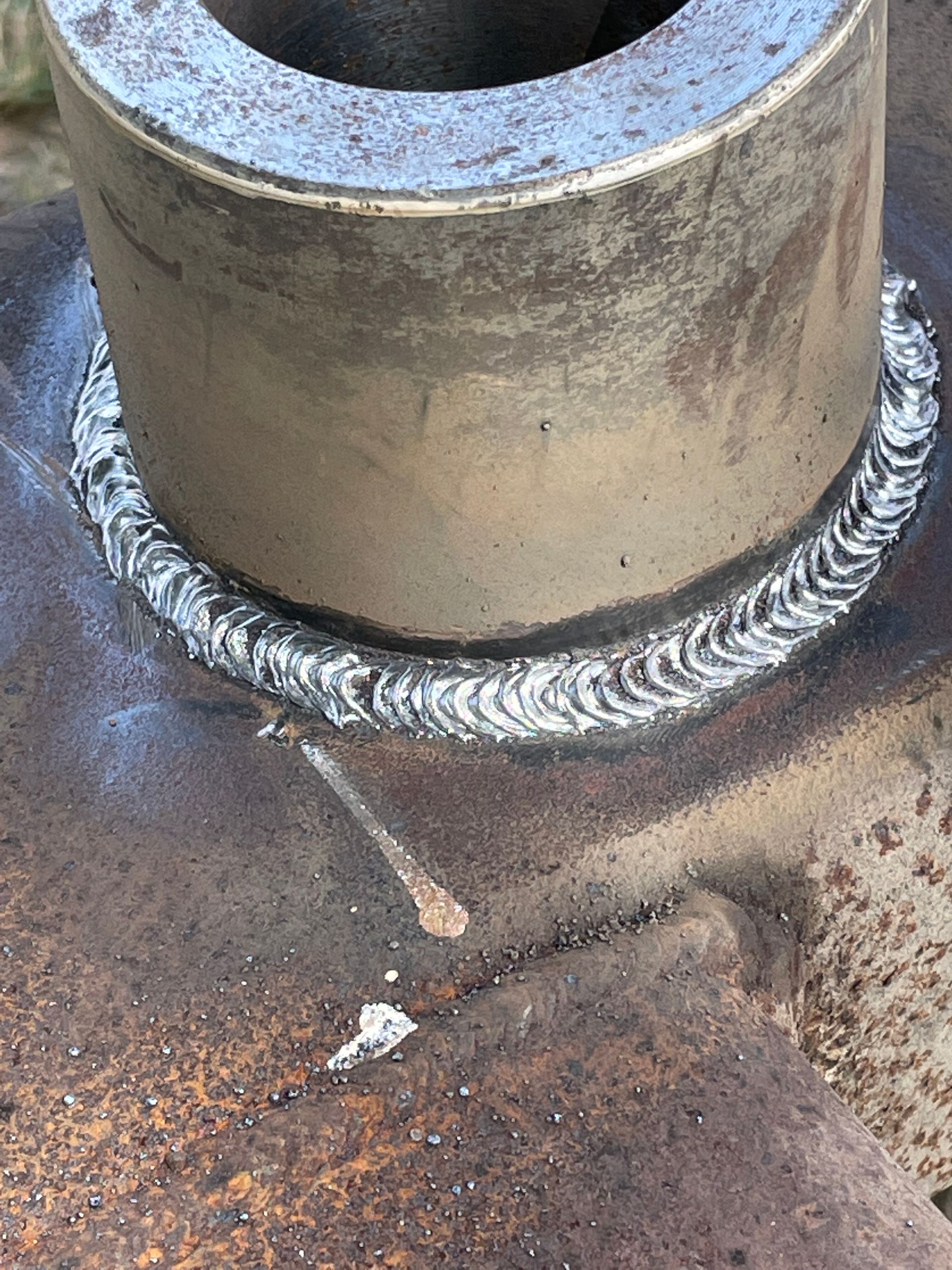 Close-up of a welded metal pipe joint on a rusty steel surface