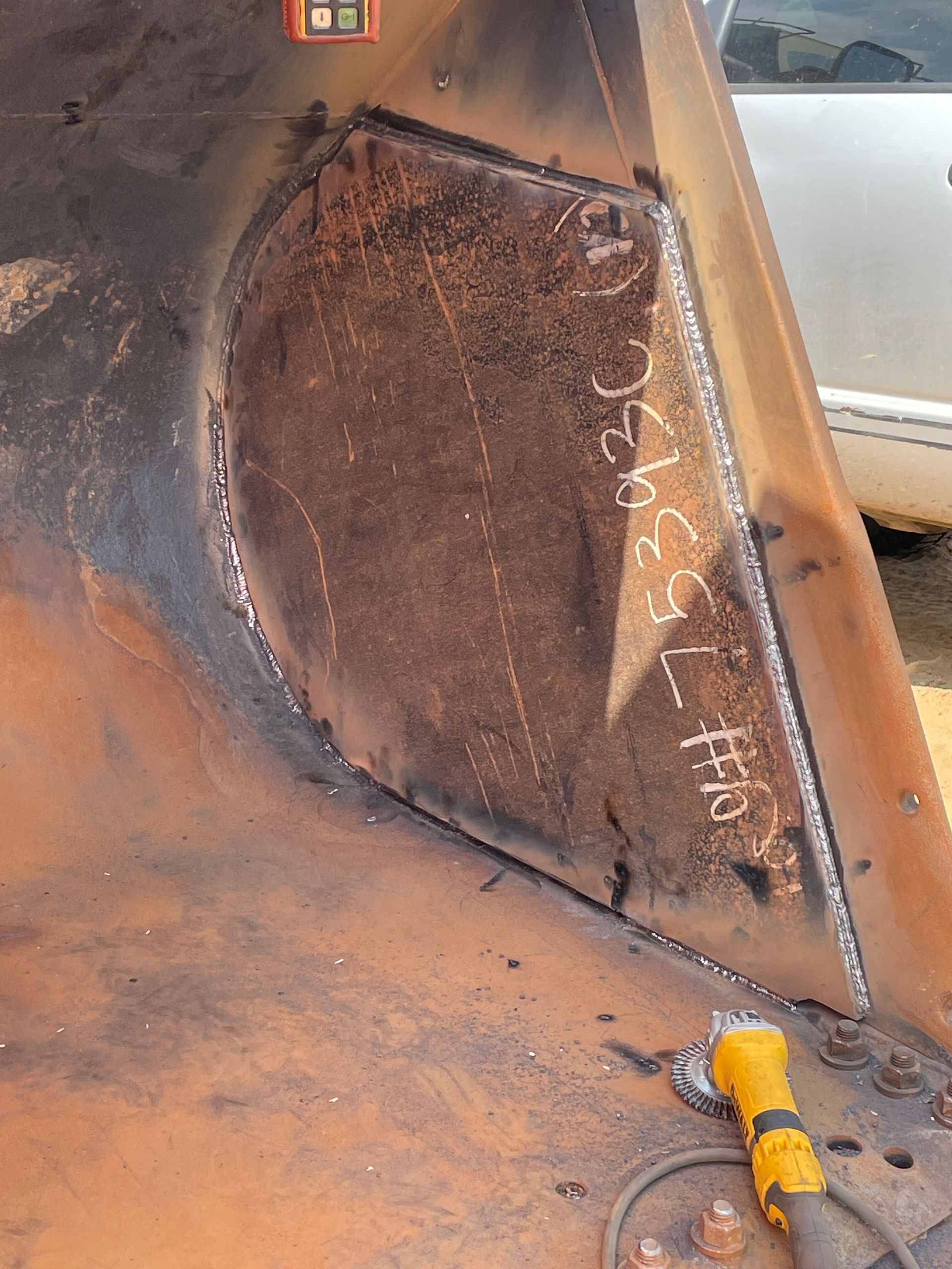 Rusty metal panel inside industrial machinery, with black scorch marks and a yellow cable at the bottom.