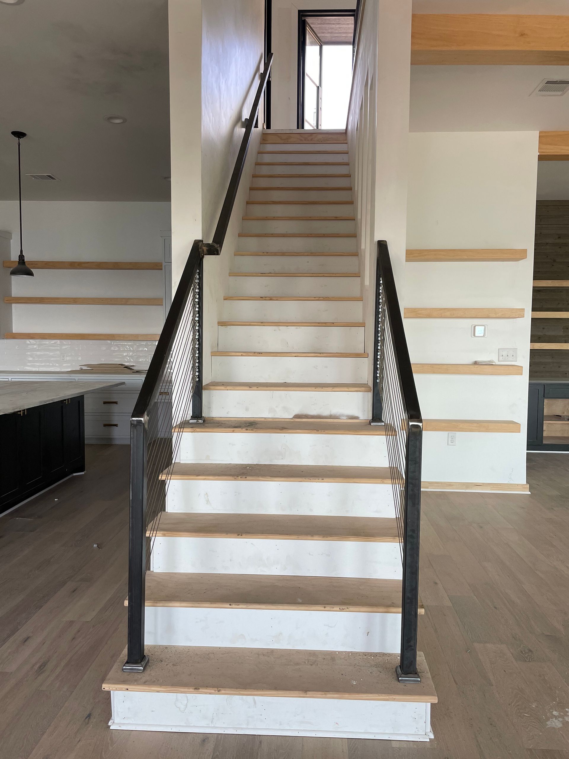 Staircase with white steps, dark railings, and beige walls in a modern interior.