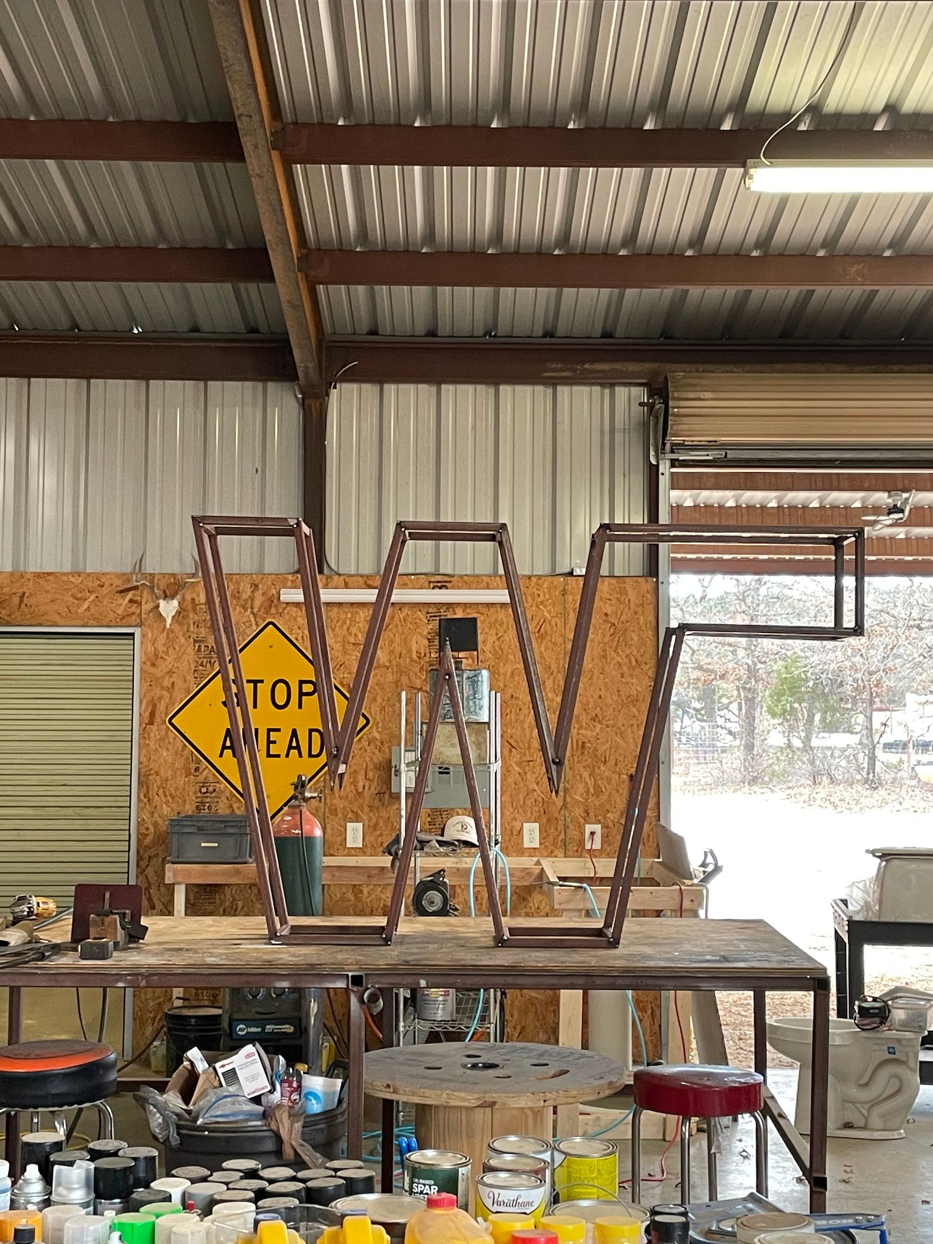 Workshop with ladders, tools, and a workbench under a corrugated metal roof