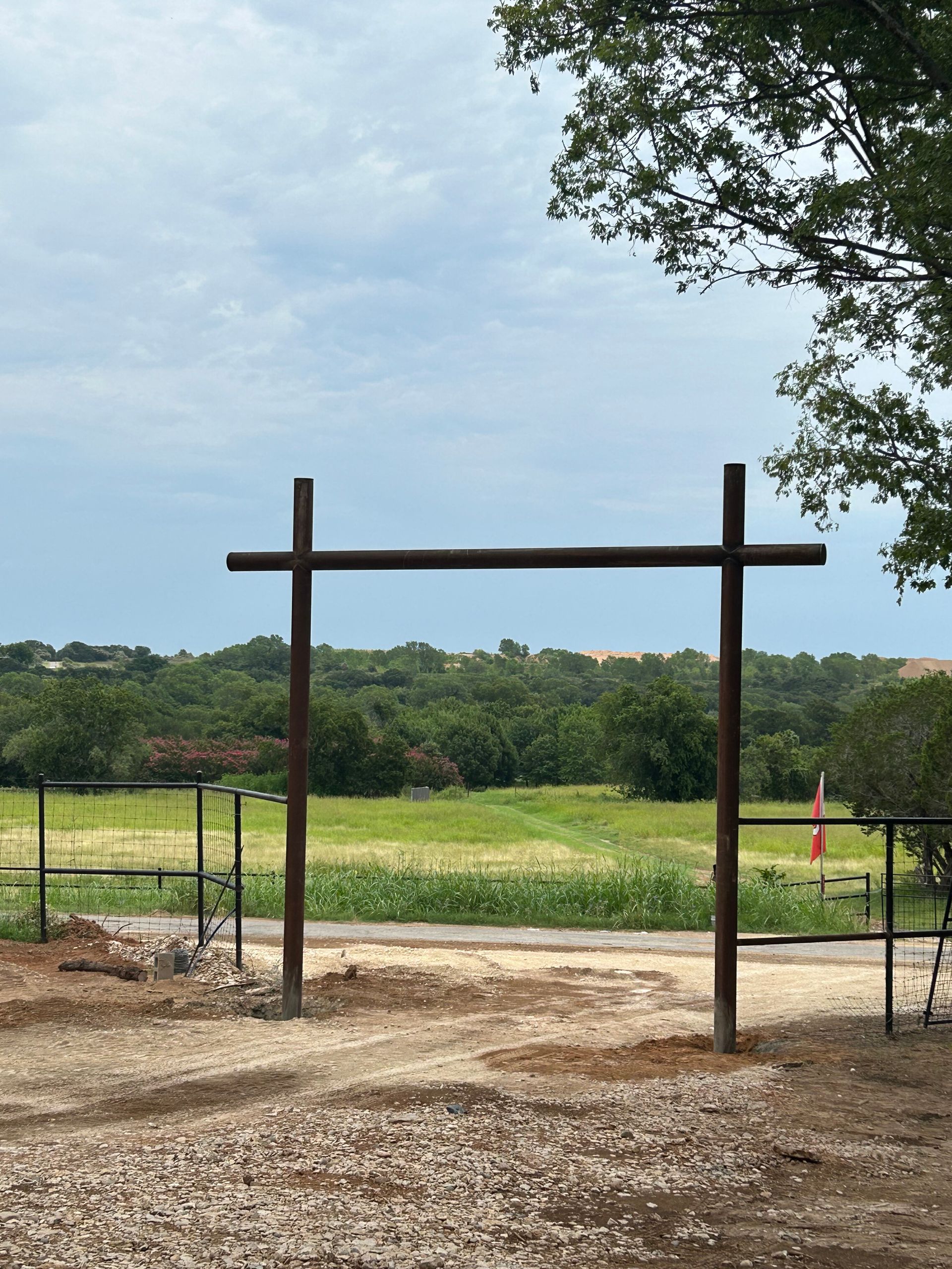 Rustic wooden gate frame overlooking a grassy field under a cloudy sky