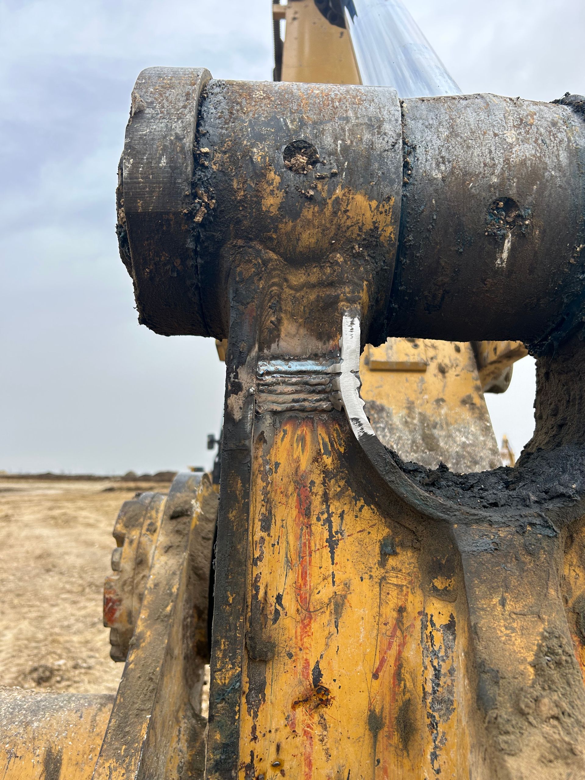Close-up of a rusty excavator arm and hydraulic joint in a dry construction site