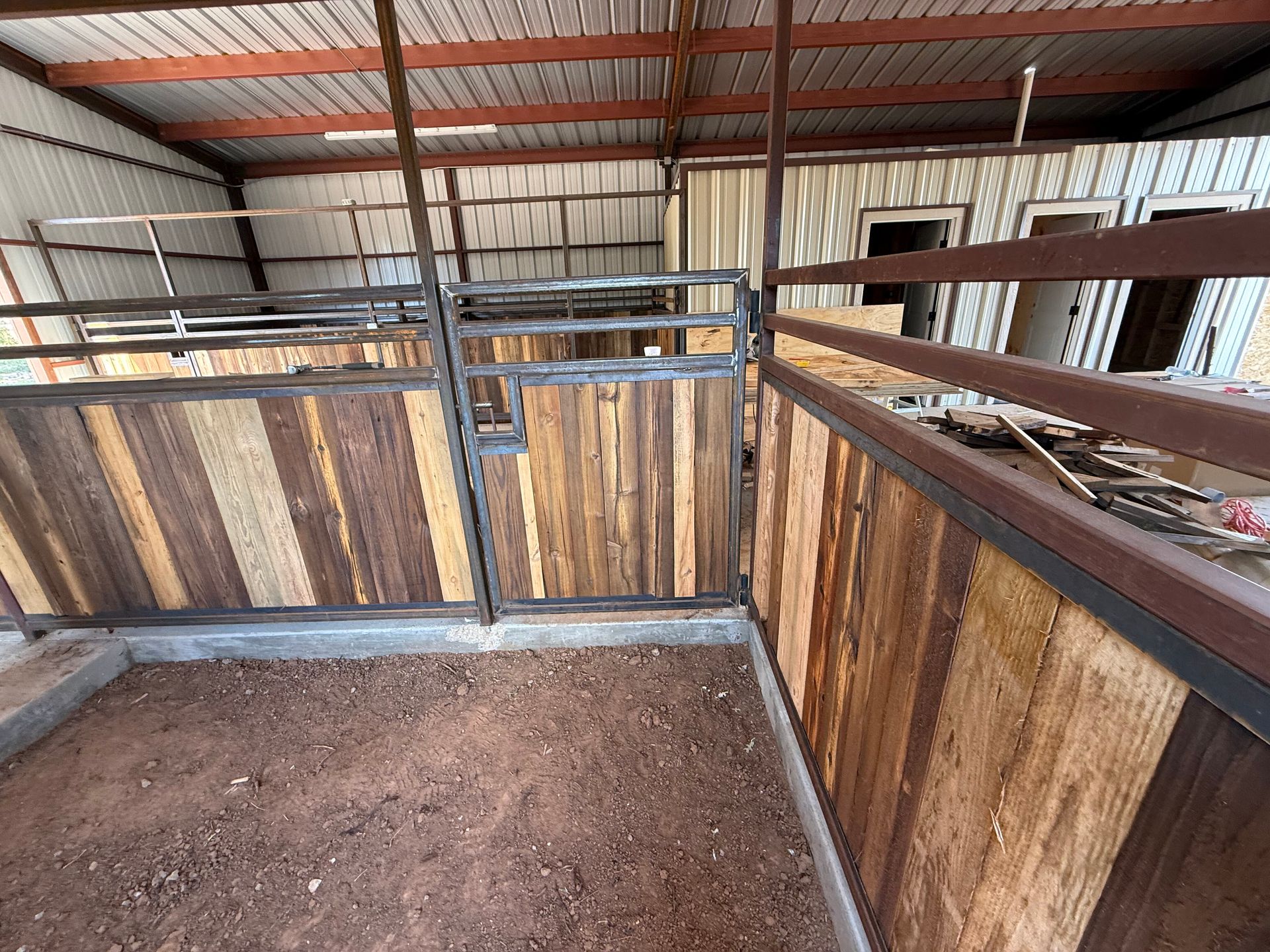 Horse stall with wooden partitions and metal rails in a barn interior