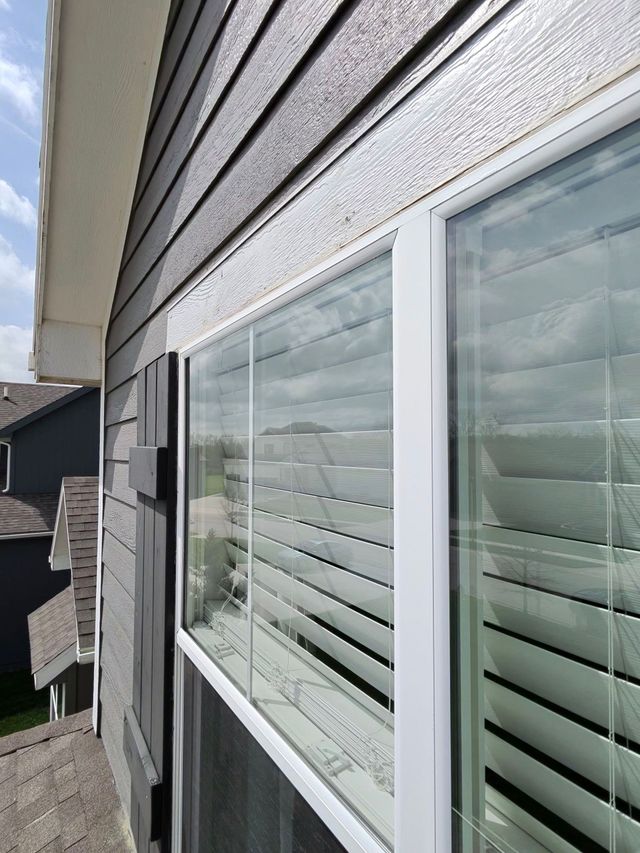 House exterior with white siding and a row of windows with closed blinds on a cloudy day