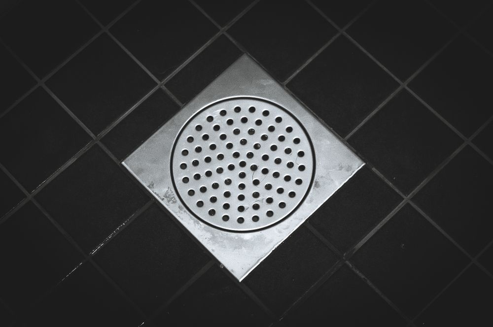 Square Metal Shower Drain in Black Tile Floor — Waves Plumbing in Gosford, NSW