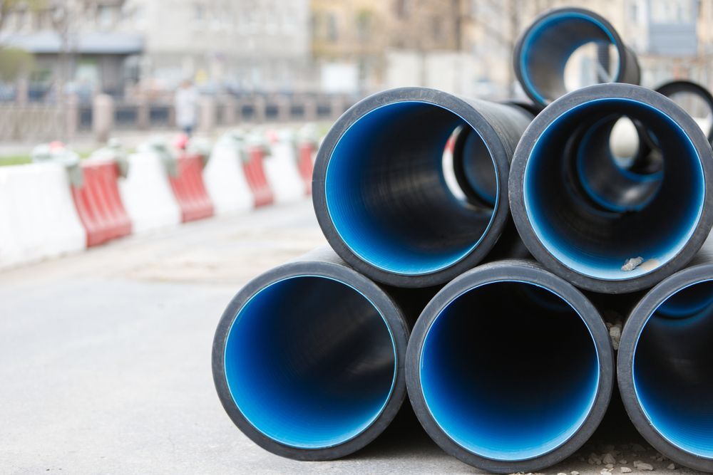 Black and Blue Plastic Pipes Stacked Outdoors — Waves Plumbing in Central Coast, NSW