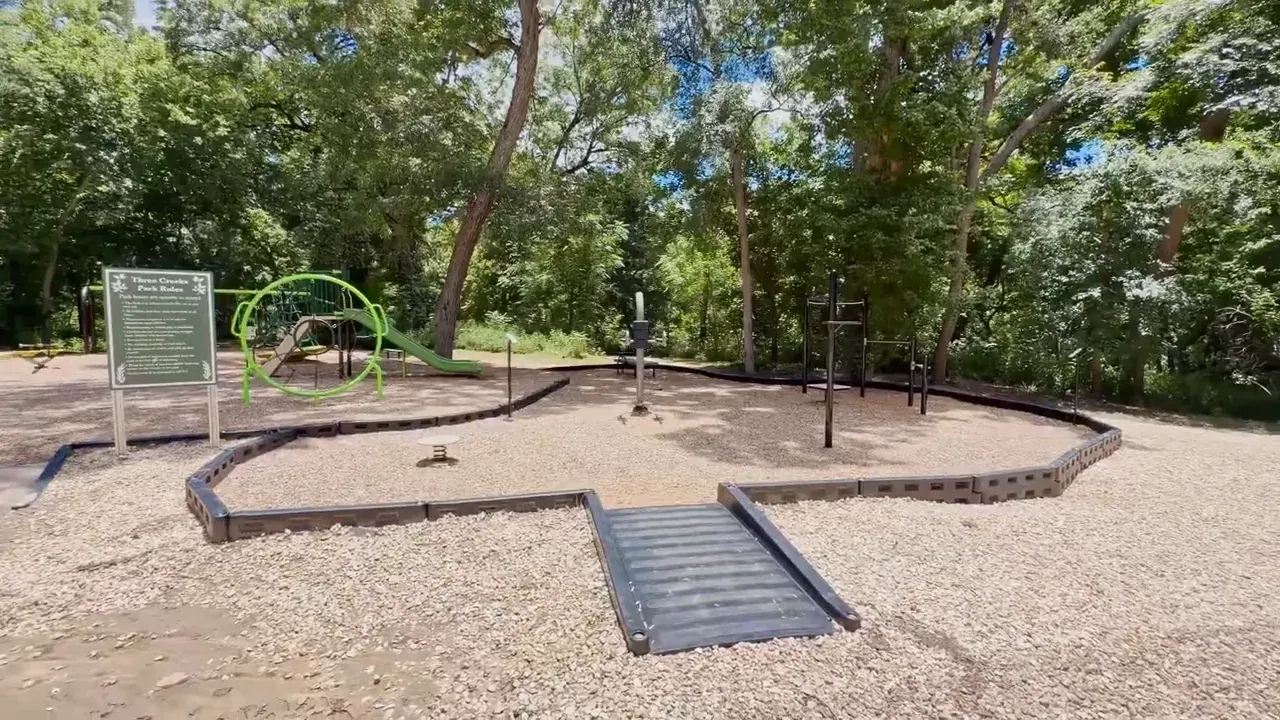Playground and fitness area with gravel surface surrounded by trees