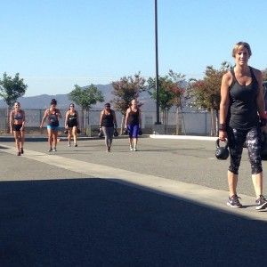 A group of women are walking down a sidewalk holding kettlebells.