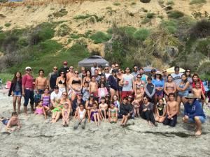 A large group of people are posing for a picture on the beach.