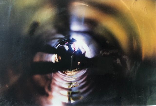Blurry, abstract view down a cylindrical structure. Gold, yellow and black tones dominate.