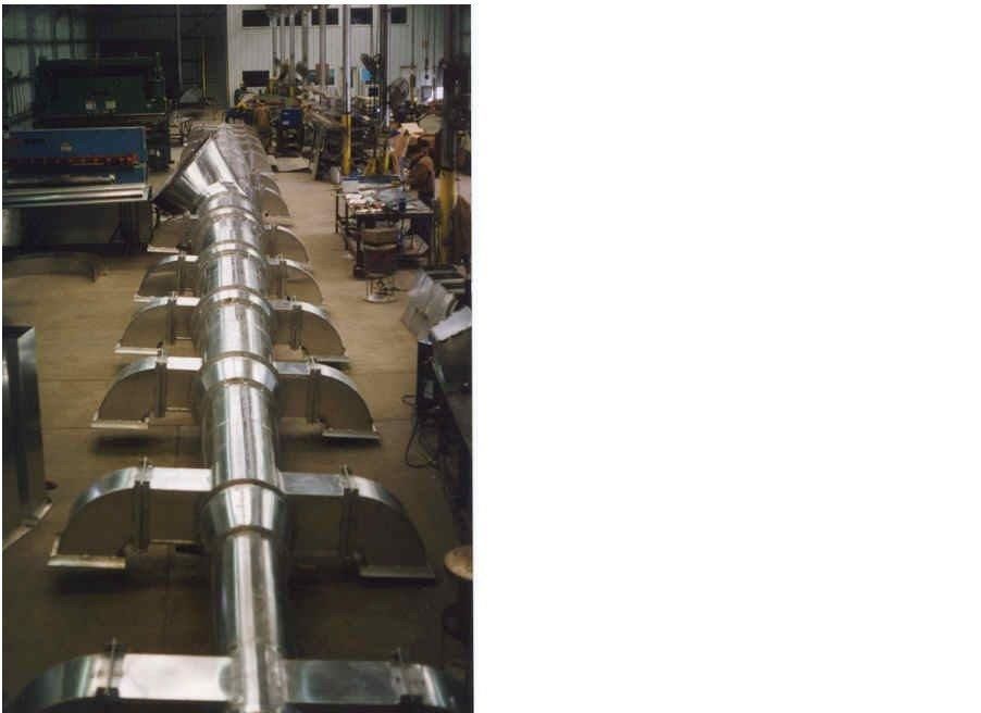 Long metal structure with attached panels, lying in a factory.