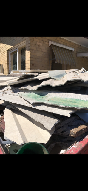 A pile of cardboard sitting on top of a roof in front of a house.