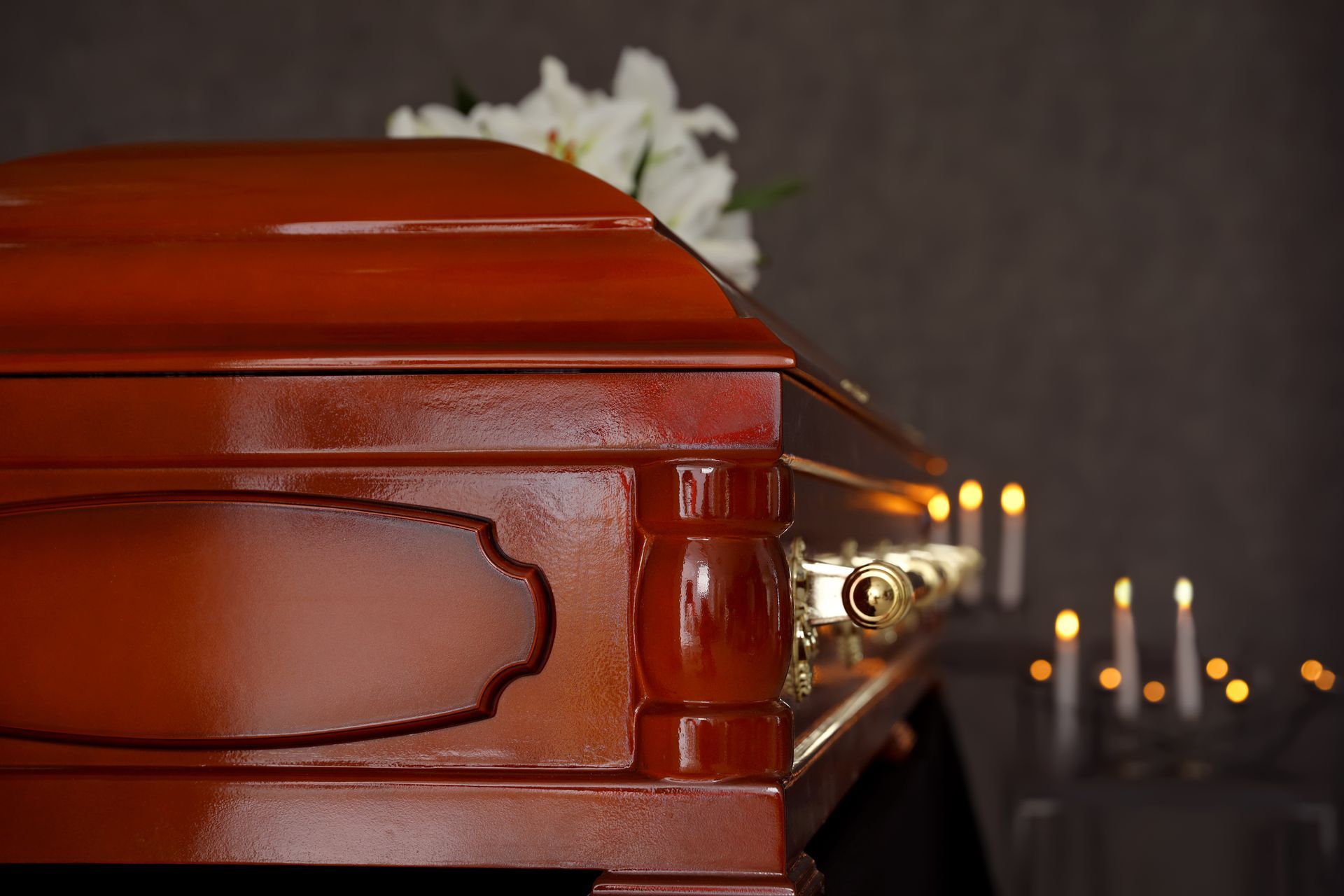Red casket with white flowers and candles in a dim funeral setting
