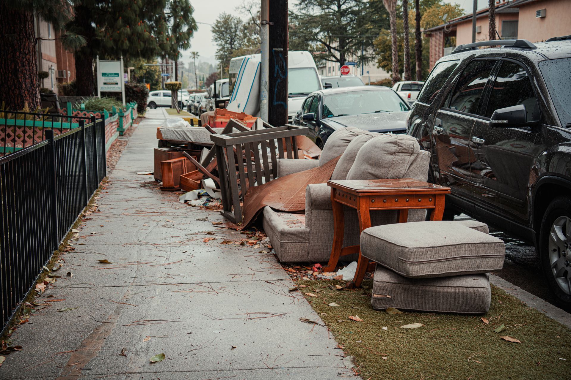 Discarded furniture and household items lined along a residential sidewalk. Discarded furniture and household items lined along a residential sidewalk.