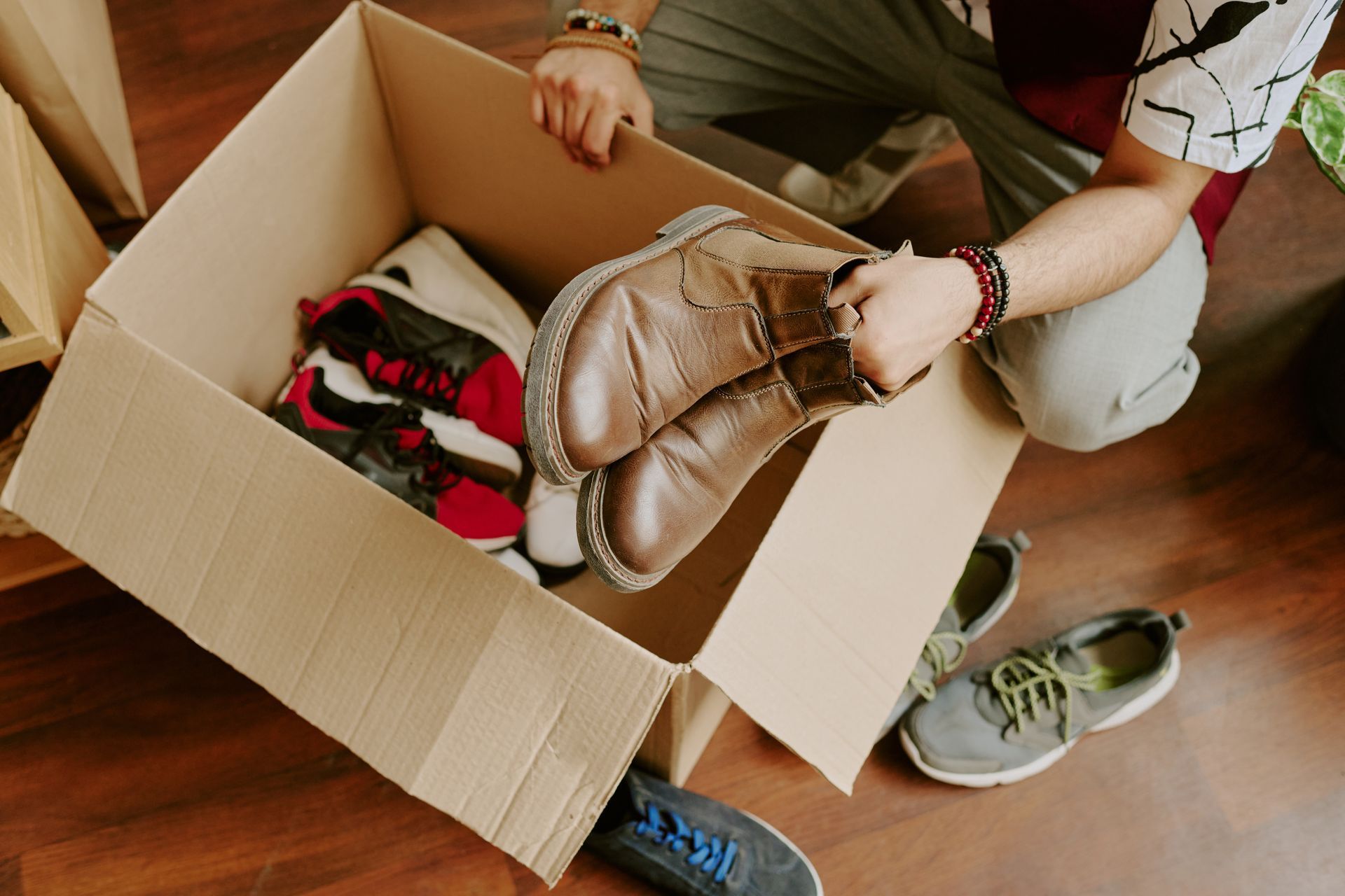 A person is sorting shoes into a cardboard box. A person is sorting shoes into a cardboard box.