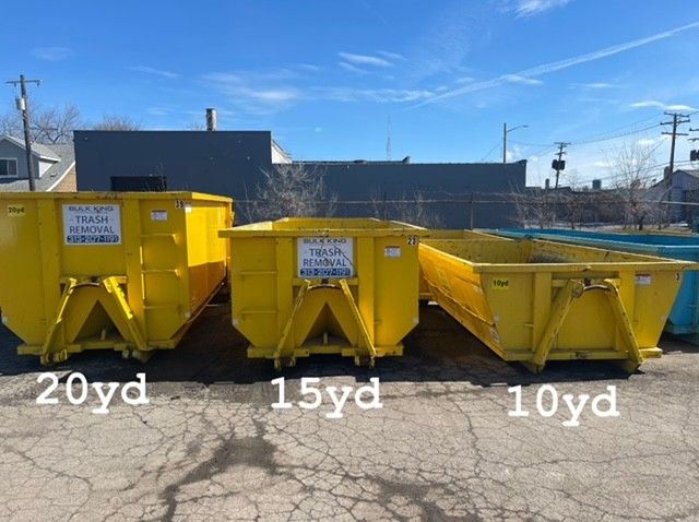 Three yellow dumpsters lined up side-by-side in an outdoor lot, labeled 20yd, 15yd, and 10yd by size.