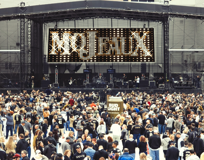 Crowd at an outdoor concert facing a large stage with a bright “MOTiMIX” sign