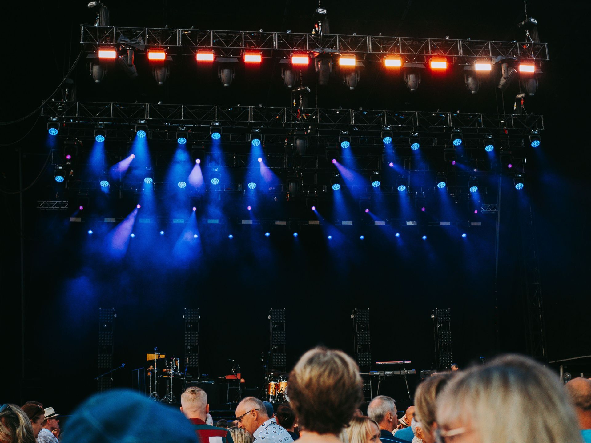 Blue and red stage lights over a concert crowd under a dark truss rig