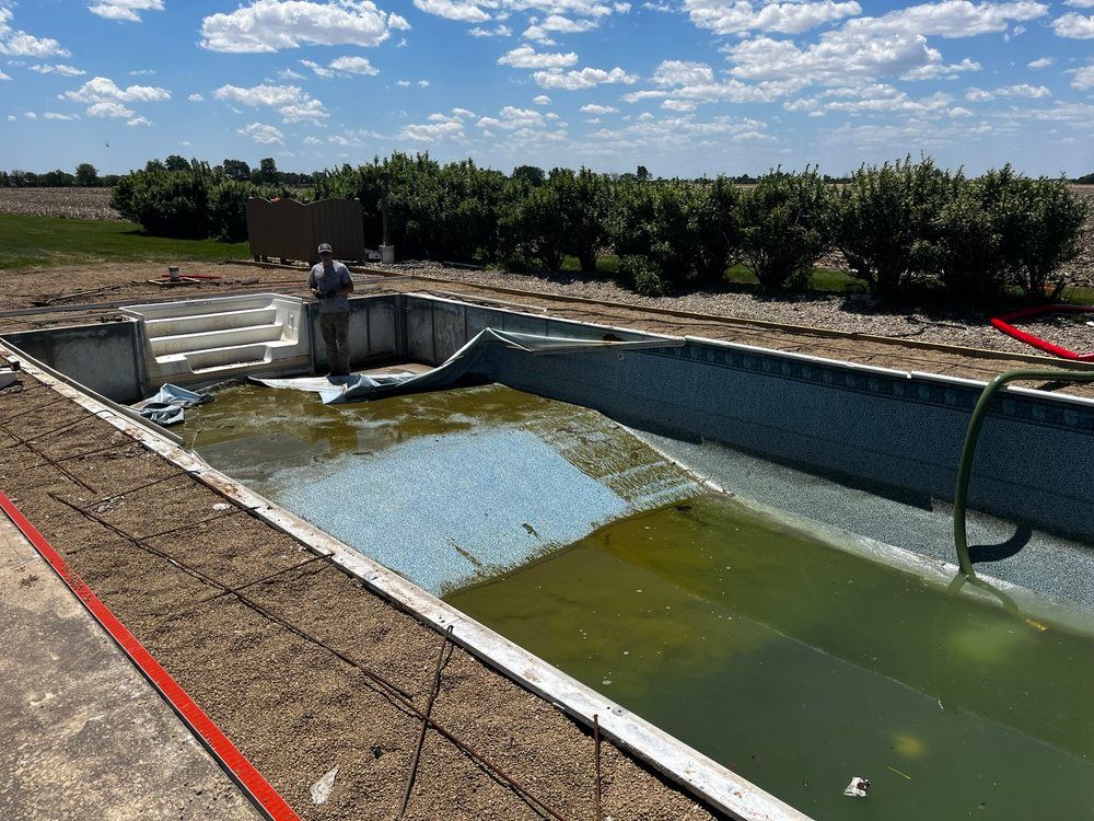 A man is standing next to an empty swimming pool.