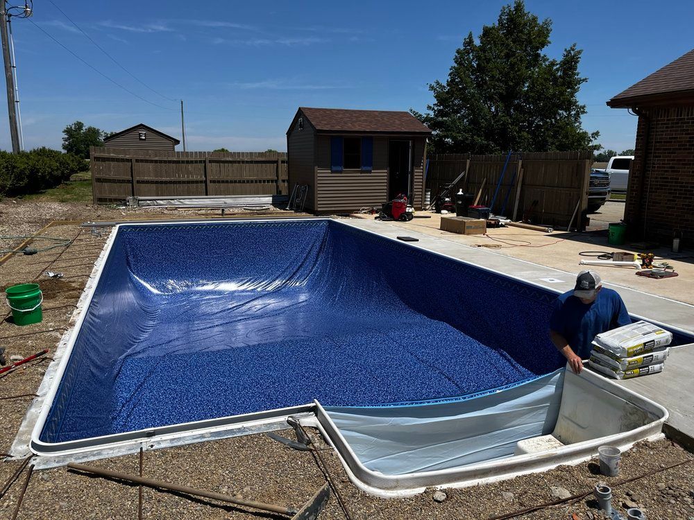 A man is working on a swimming pool in a backyard.