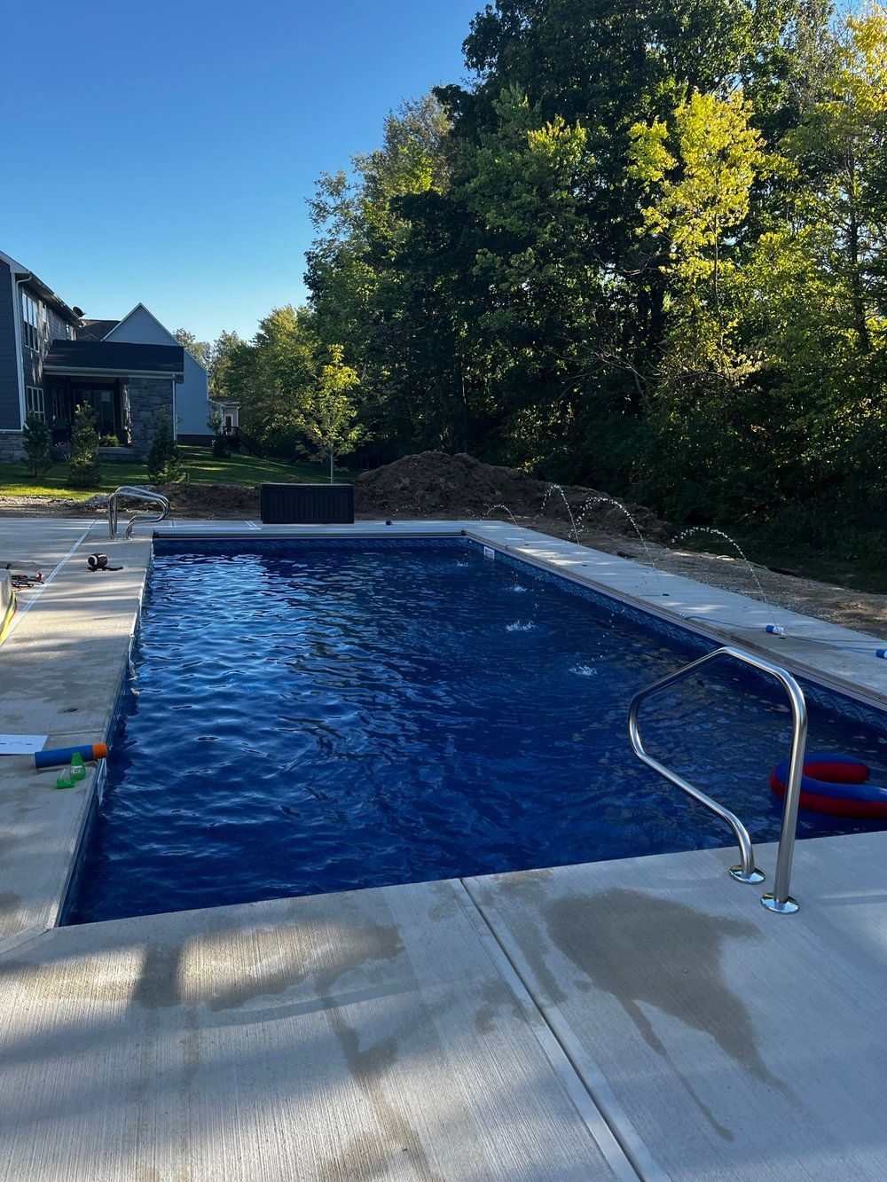 A large swimming pool is being built in the backyard of a house.