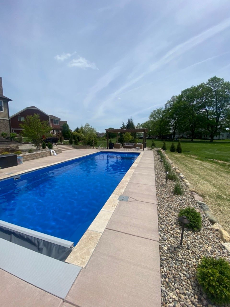 A large swimming pool is lit up at night in front of a house.
