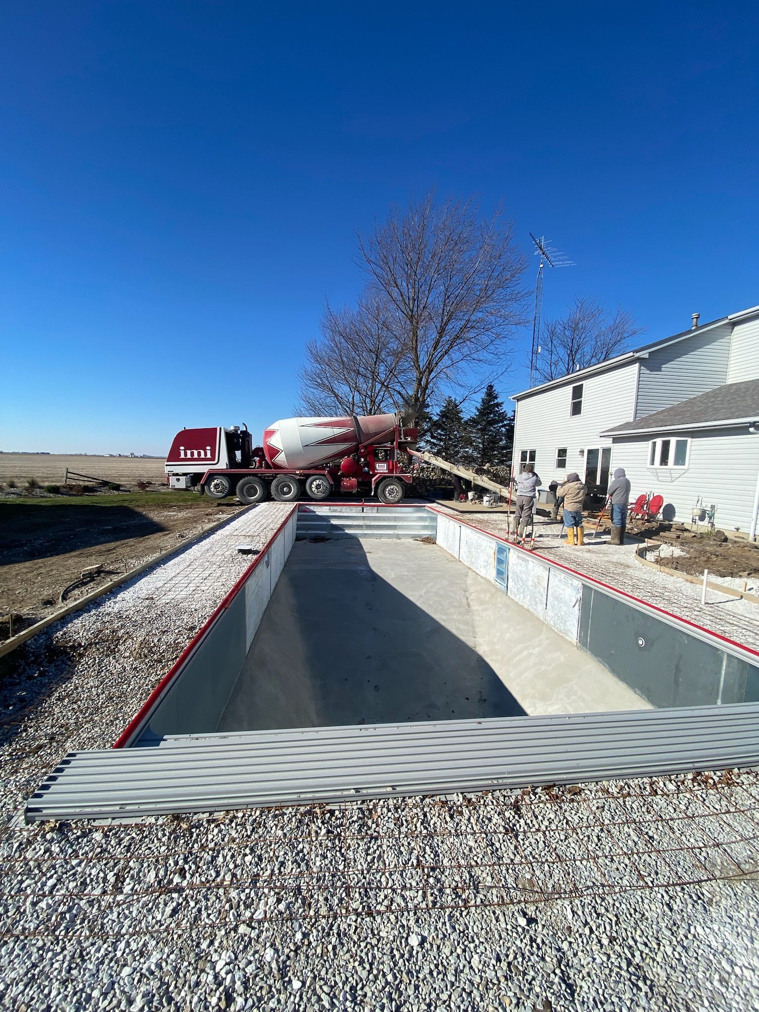 A concrete truck is pouring concrete into a swimming pool.