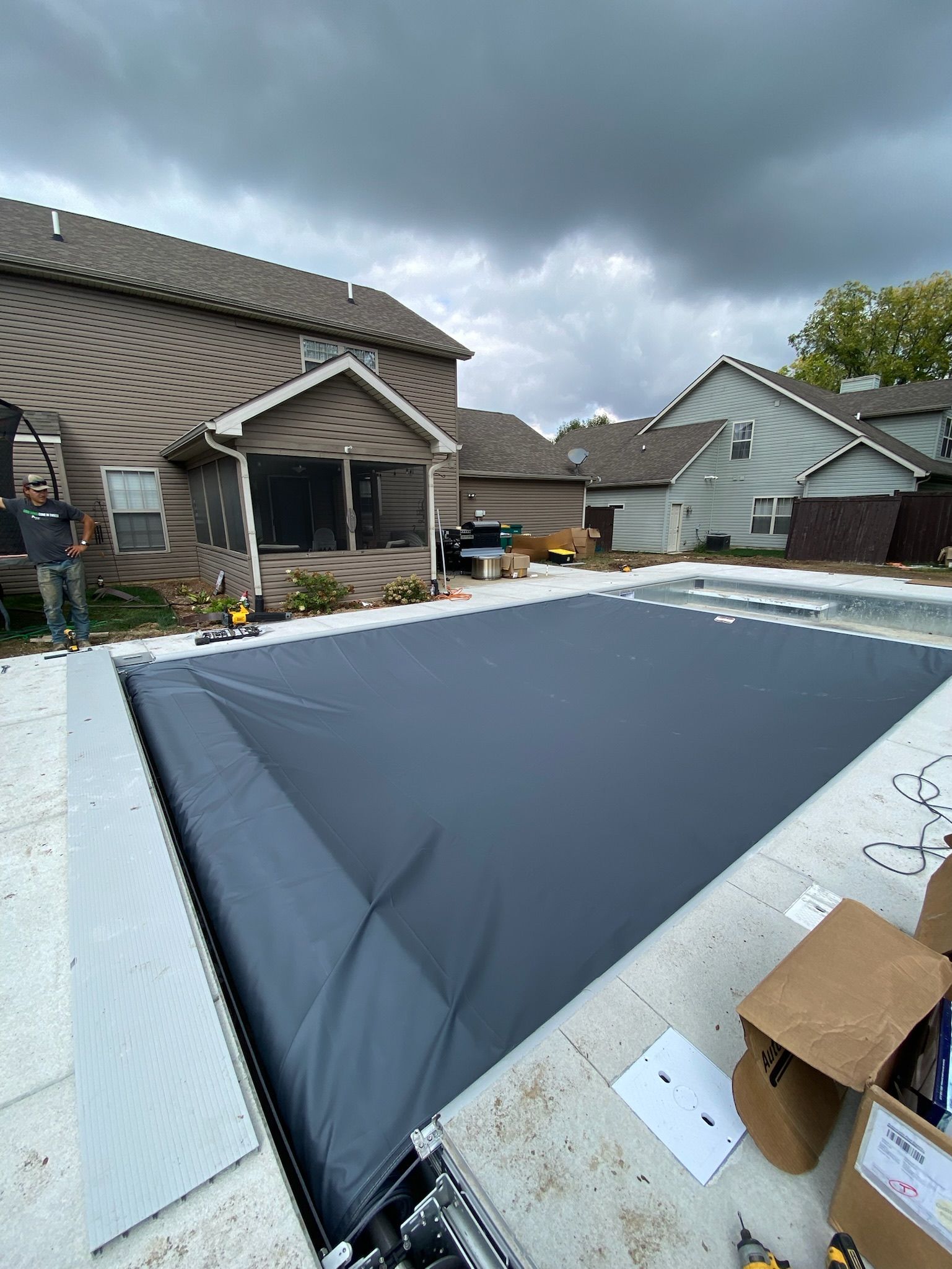 A large swimming pool is lit up at night in front of a house.