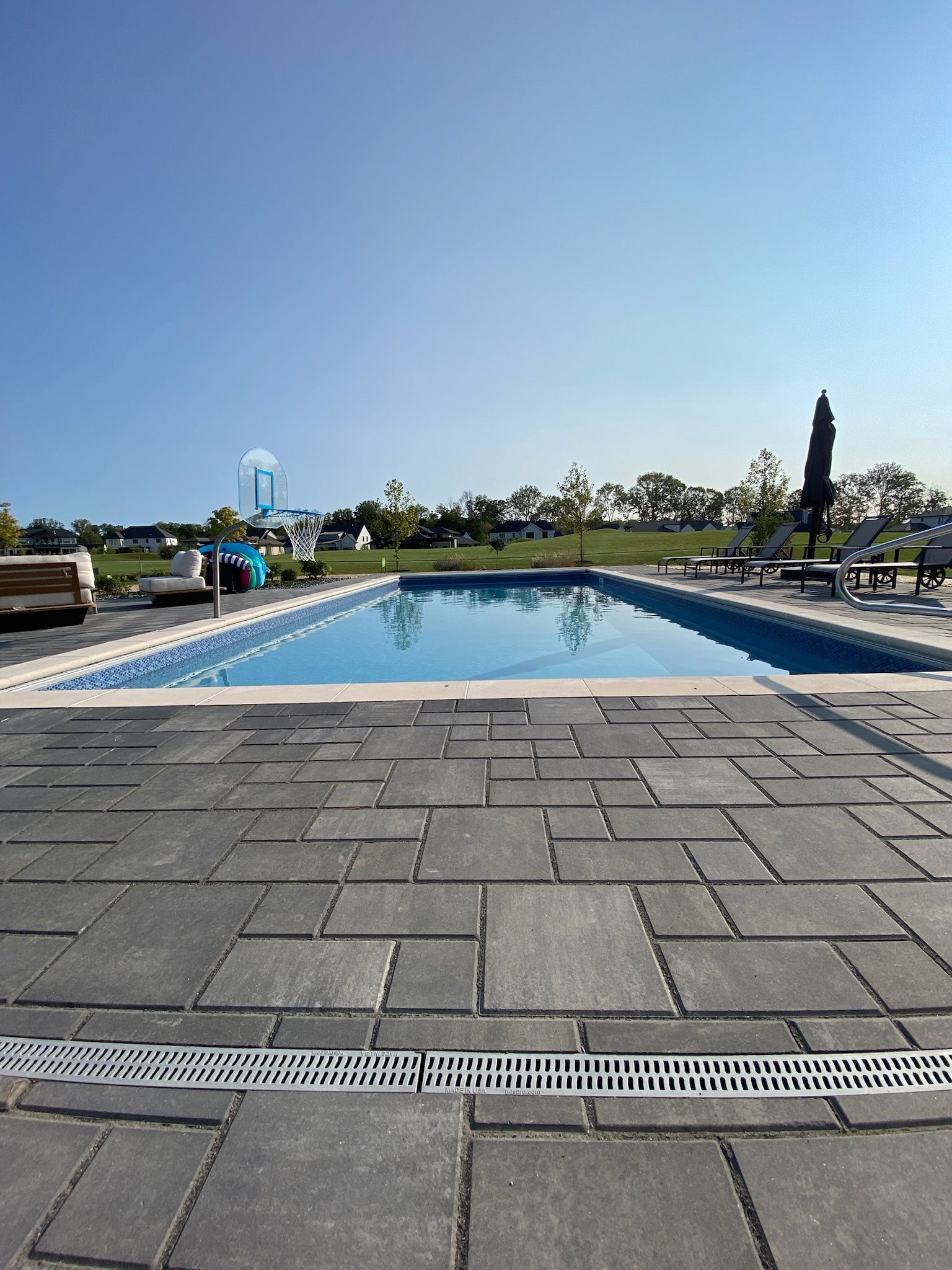 A large swimming pool is surrounded by chairs and umbrellas on a sunny day.