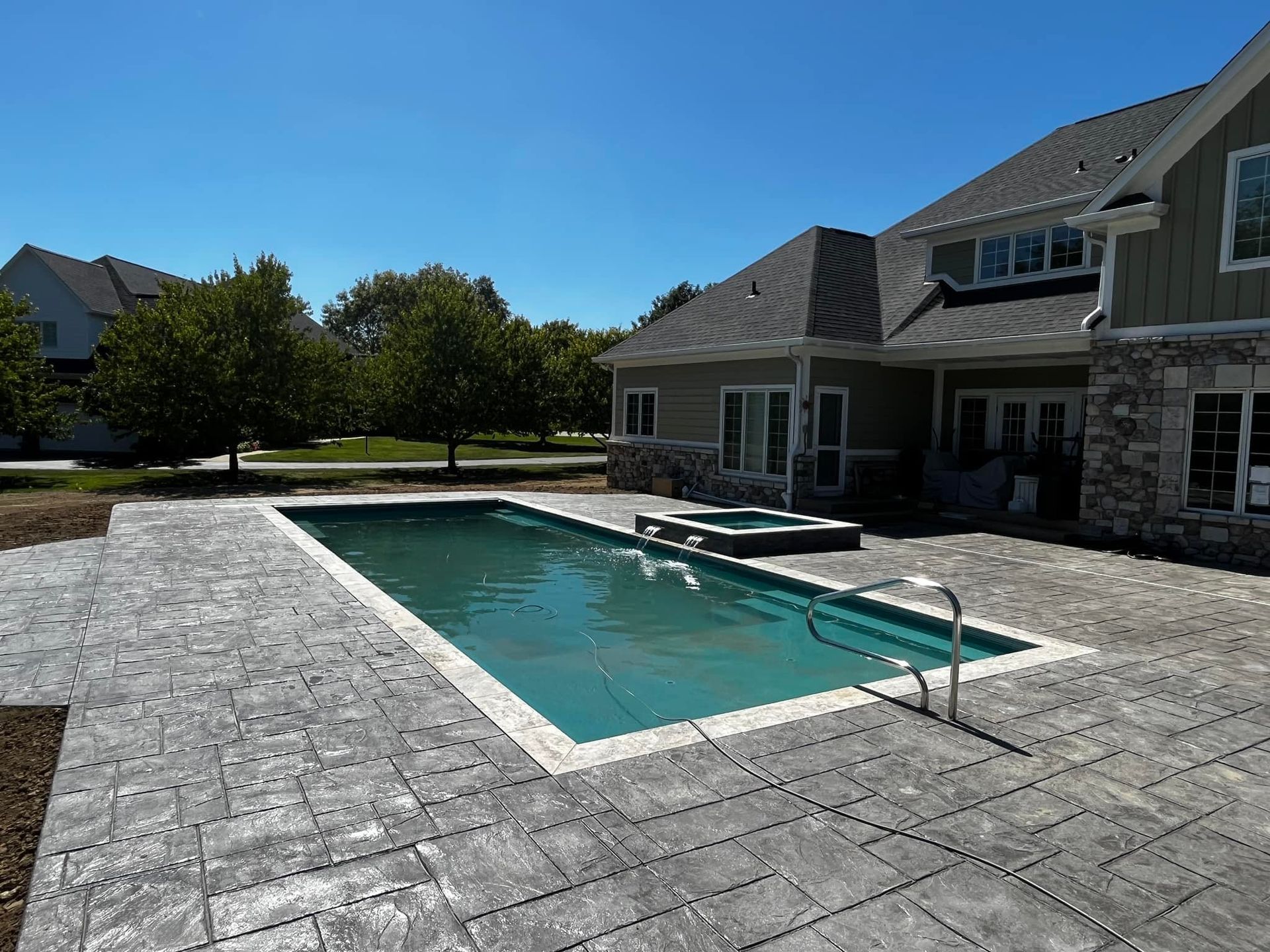 A large swimming pool is in the backyard of a house
