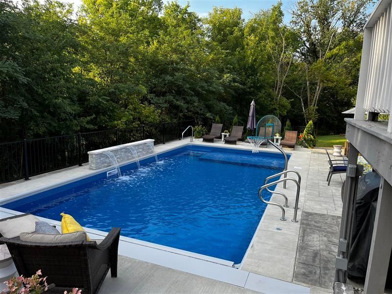 There is a large swimming pool in the backyard with a waterfall.