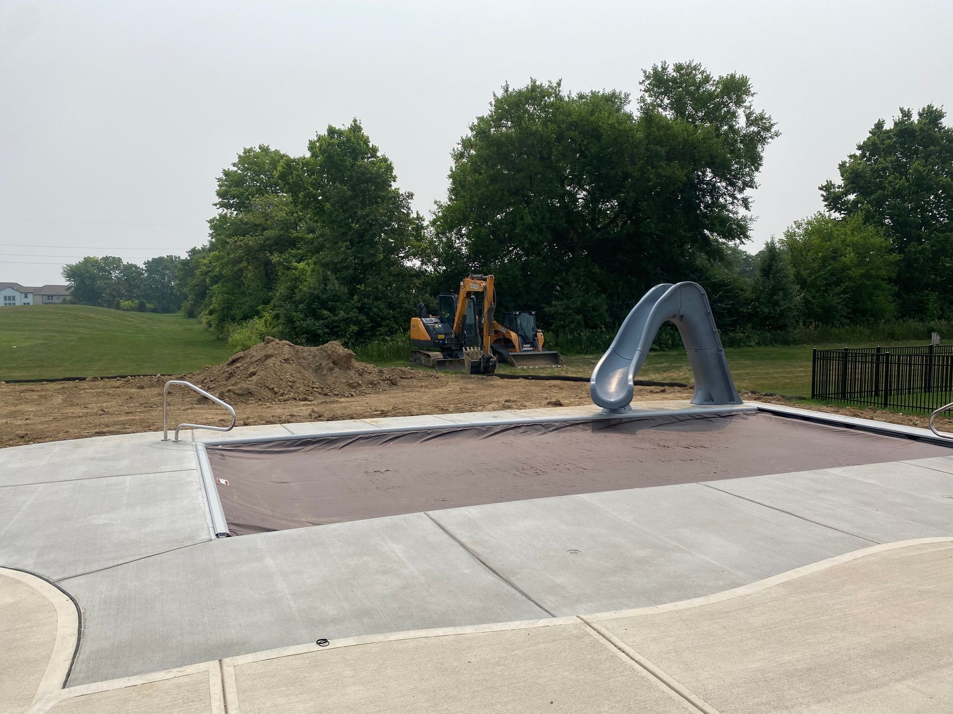 A large swimming pool is being built in the backyard of a house.