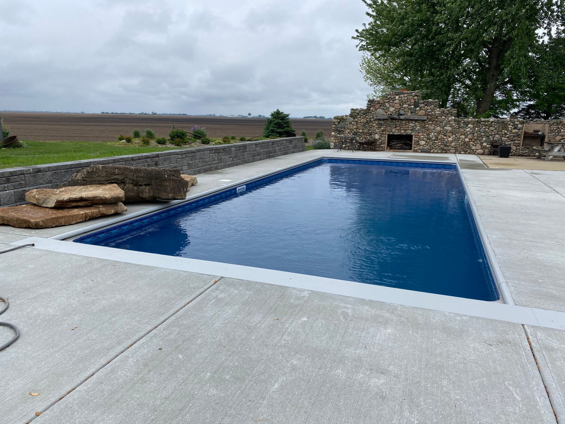 A man is standing next to a swimming pool being built in a field.