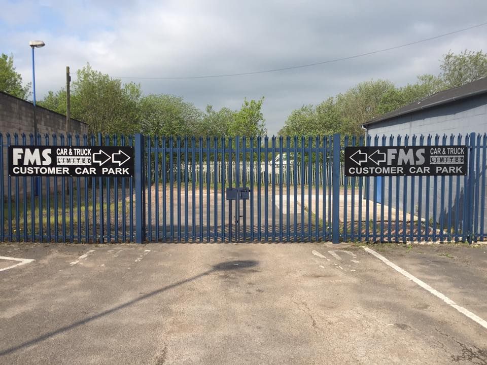 A blue fence with a sign that says fms customer car park