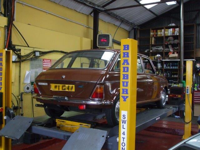 A brown car on a lift with the word bradbury on it