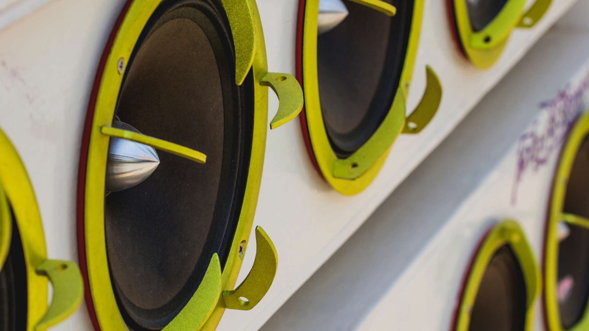 Close-up of yellow-rimmed speakers mounted in a white audio panel