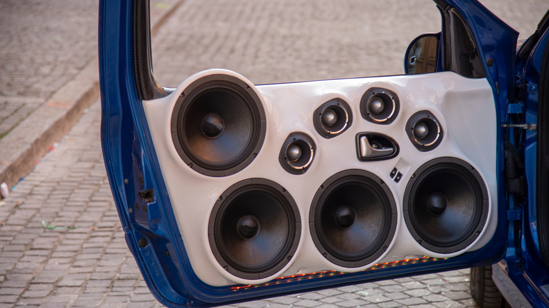 Open car door with custom blue speaker panel and multiple audio speakers