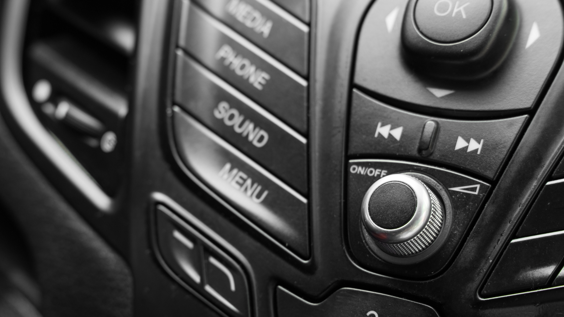 Close-up of a car dashboard control panel with buttons and a central knob