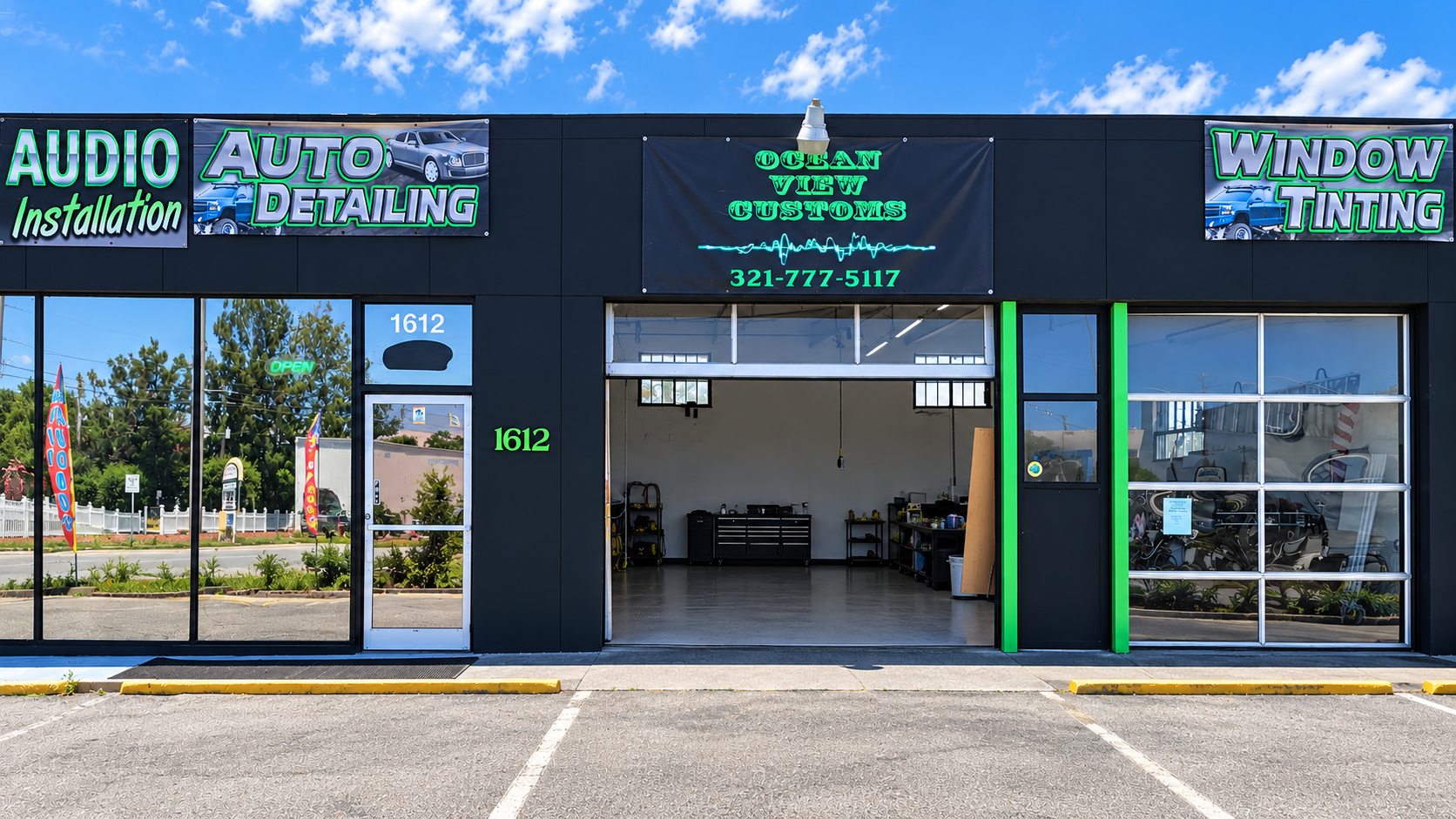 Auto detailing and window tinting storefront with open garage and parking lot in front