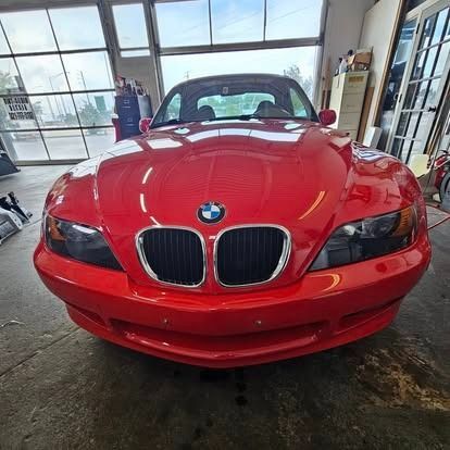 Front view of a red BMW sports car in a garage, with large windows in the background