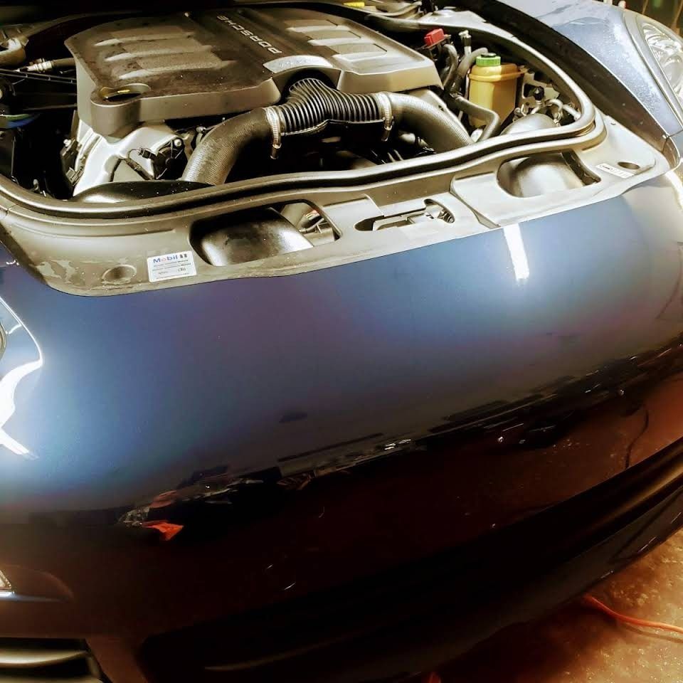Front view of a car with the hood open, showing the engine compartment.