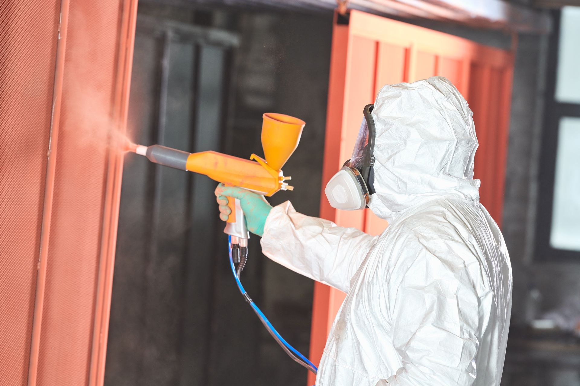 Photograph showing a person wearing full protective gear, including a white hazmat suit, gloves